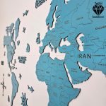 نقشه چوبی جهان با نام کشورها رنگ آبی - از زاویه نزدیک که کیفیت حکاکی نام کشور ها و مرز ها نمایش داده شده که همه نقشه مشخص هست و و در آن علاوه بر نقشه جهان به دیوار نصب هست بلکه برای تزیین نقشه از لنگر و جهت نما و کشتی و هواپیما استفاده شده